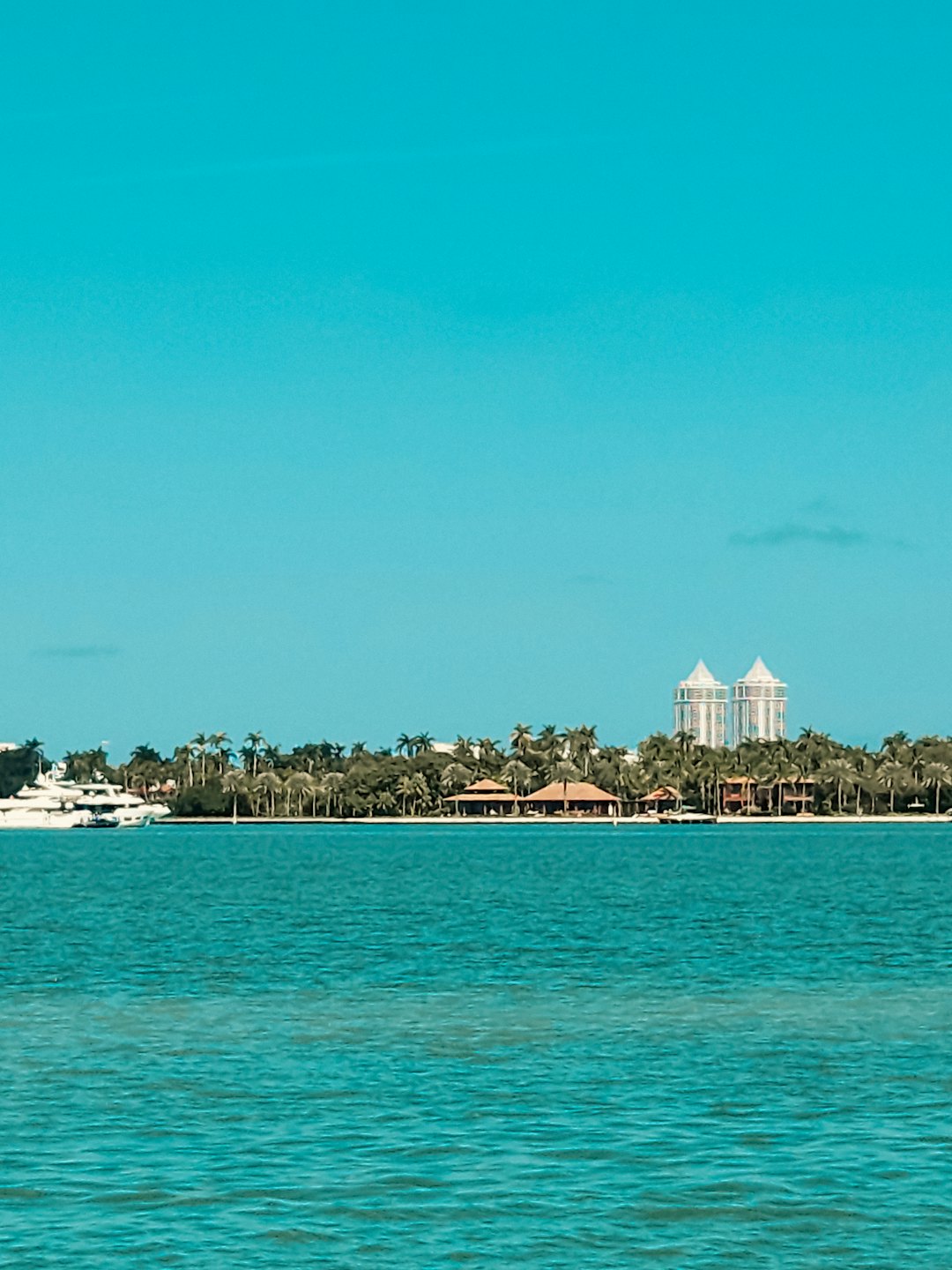 Tropisch eiland met palmbomen en een jacht op turquoise water.
