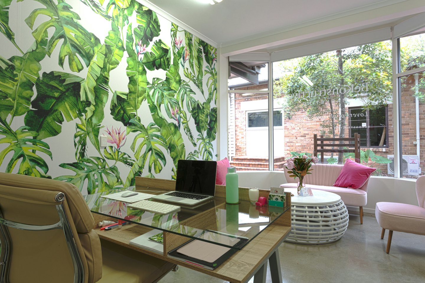 Modern kantoor met een houten bureau en een bloemenmuurschildering.